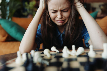 Woman contemplating her next move during a game of chess, deep in thought with head in hands at...
