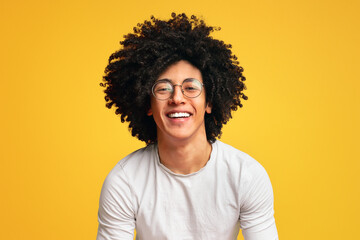 Happy millennial black guy laughing on orange background