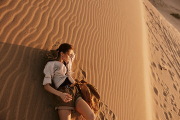 Woman laying on sand dune in the middle of the desert under the scorching sun