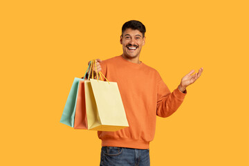 Man Holding Shopping Bags and Smiling On Yellow Background