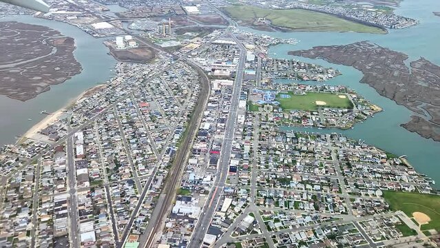 Breathtaking view from airplane window during landing at New York airport encompasses both coastal landscape of Atlantic Ocean and charming architecture of suburban neighborhoods.