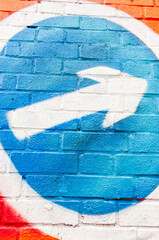 White arrow graffiti sprayed on blue brick wall