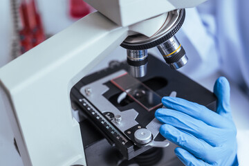 Hands of a doctor or female doctor collecting blood sample tubes from rack with analyzer in lab. Doctor holding blood test tube in research laboratory red blood cells