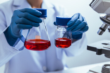 Hands of a doctor or female doctor collecting blood sample tubes from rack with analyzer in lab....