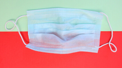 Blue surgical mask on a two-color background. Medical mask on a green-red background, top view....