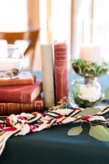 Obraz na płótnie Canvas A unity rope is on a table with stacked old books in a romantic table setting at a book-themed wedding
