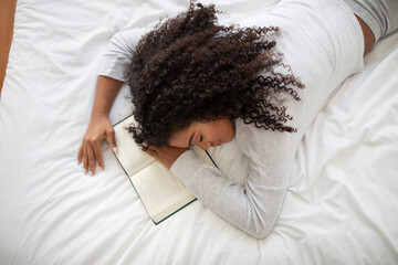 Young Woman Asleep on a White Bed With a Book
