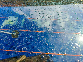 Raindrops on the clean car glass image with silver color car on the background