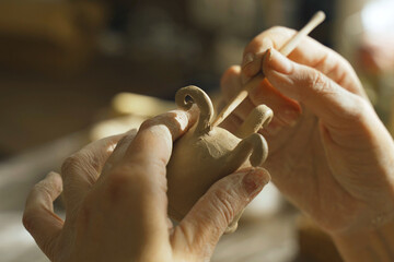 A woman makes a small flower pot from clay and works with a brush.