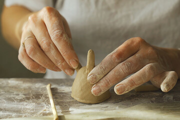 A woman makes a ceramic pot and attaches the legs.