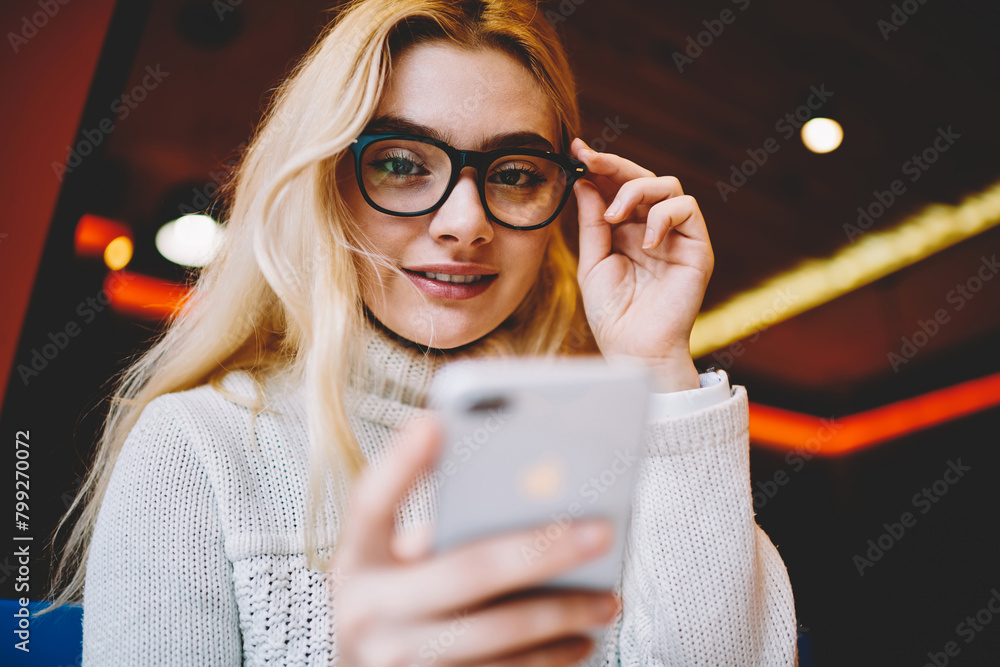 Aufkleber selective focus on female blogger looking at camera holding smartphone for checking update in networ