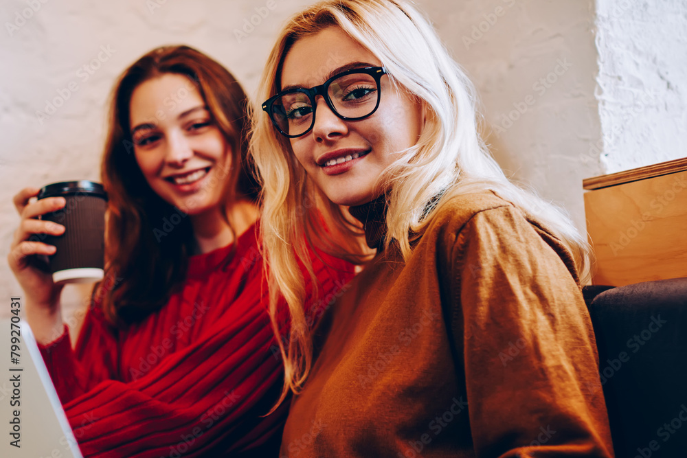 Poster portrait of hipster girl browsing on netbook resting on break with best friend, positive female teen