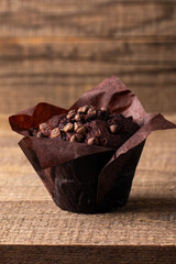 Chocolate dark muffin with chocolate chips and drops on a wooden table 