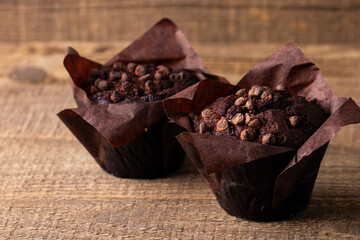 Chocolate dark muffin with chocolate chips and drops on a wooden table 