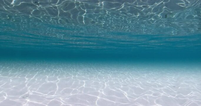 Blue ocean underwater with white sandy bottom and waves. Sea texture