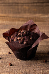 Chocolate dark muffin with chocolate chips and drops on a wooden table 