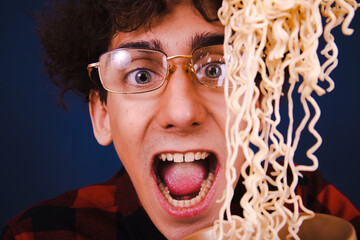 Retro style. A young attractive guy eats Chinese noodles.