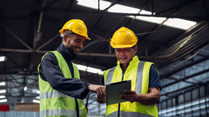 Two men in safety gear are looking at a tablet