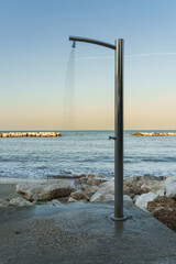 An outdoor beach shower stands against a serene sea backdrop, embodying tranquility and the concept...