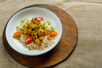 Thai chicken with rice in Pad Thai sauce on a plate on a wooden stand on the table