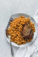 top view of Jollof rice and fried chicken on a white plate, homemade nigerian jollof rice on a...