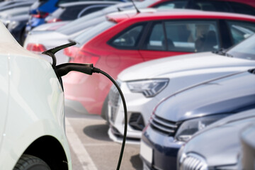 Close-up of a charging electric car on the background of parked cars