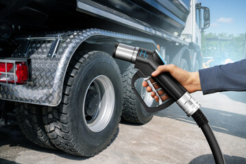 Hand with H2 nozzle on a background of hydrogen fuel cell truck. Eco-friendly commercial vehicle...