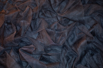 Close-up of crumpled, dark mesh fabric showcasing intricate textured details.