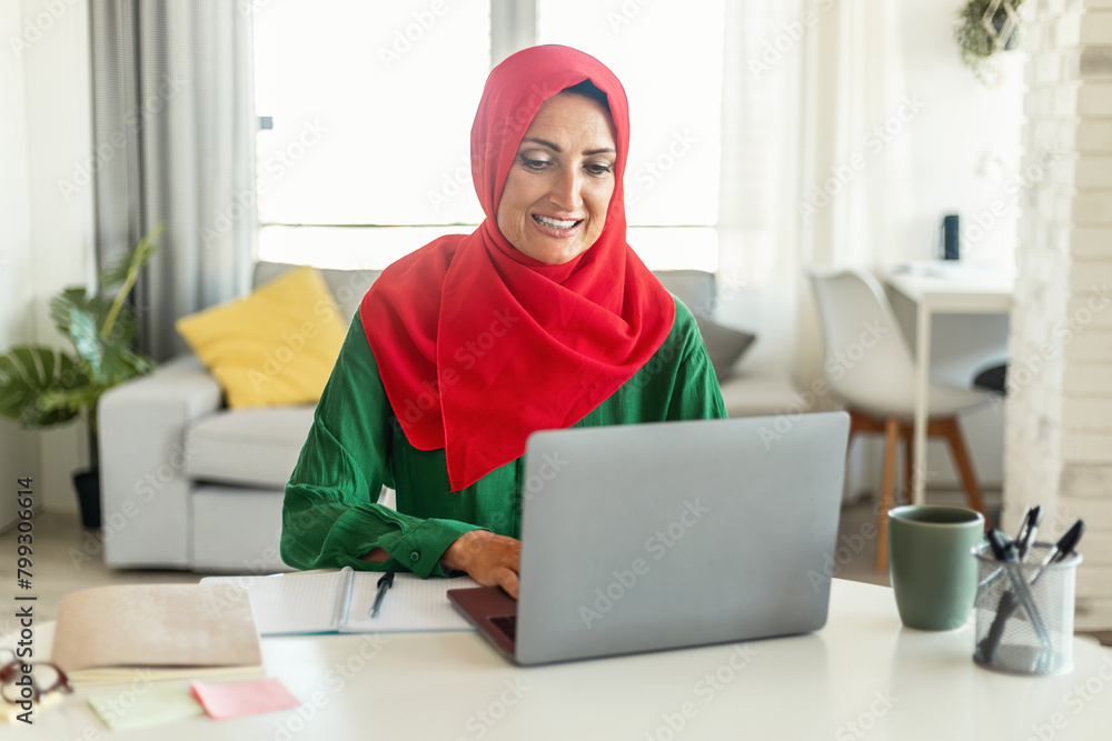 Poster woman sitting at table using laptop computer