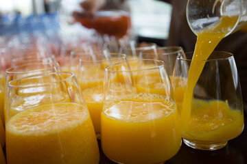 Pouring orange juice into glasses