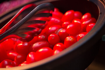 Cherry tomatoes in a plate with tongs