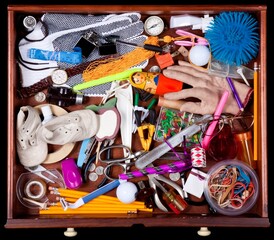A wooden catch-all drawer overflowing with a variety of colorful household items.
Some of the...