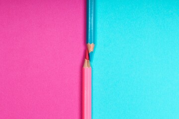 Two colored pencils, one pink and one blue, snapped in half on a colorful...