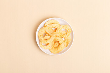 Minimalist composition with apple chips in a white ceramic plate from above on a light beige background. Healthy sweet snack.