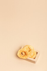 Minimalist composition in a rustic style with apple chips in a wooden box on a light beige background. Healthy sweet snack.