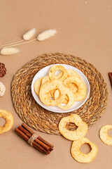 Fototapeta premium Sweet tasty apple chips in a white ceramic plate on a light beige background in rustic style. Healthy snack.