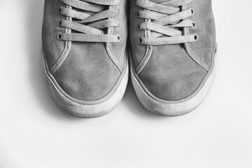 A black and white photo of a pair of gray suede sneakers with white soles.
The sneakers are laced...