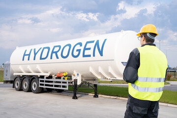 Man with digital tablet on a background of hydrogen tank trailer.	