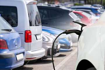 Close-up of a charging electric car on the background of parked cars