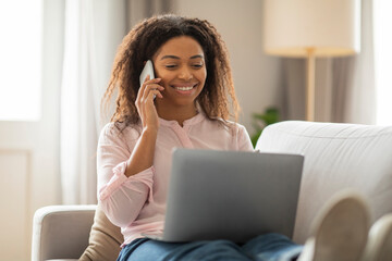 Busy African American Woman Multitasking with Laptop, Phone at Home