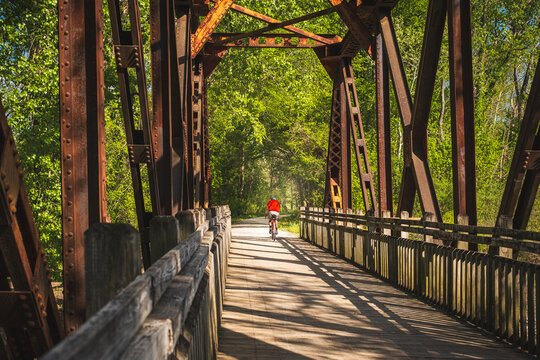 View from inside of railroad bridge  converted into recreational trail in summer; male bicyclist riding   in background