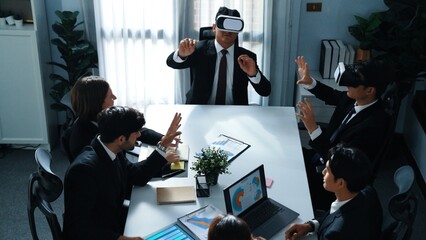 Top view of manager working on laptop and sending data analysis to business people by using VR glass headset while diverse team planning marketing strategy and looking at financial graph. Directorate.