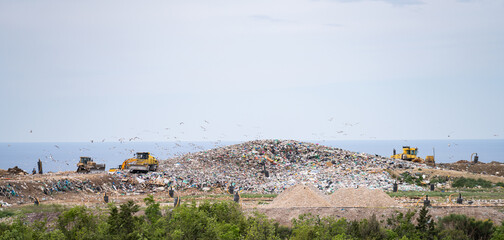 Machines are working on a dumb with sea on a background.