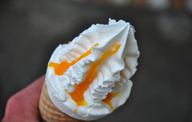 hand holds ice cream in a waffle cone sprinkled with jam. close-up and blurred background