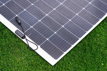 Thin flexible mobile solar panel with cable for connection.