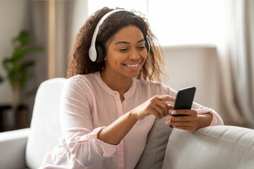 Woman Listening to Music with Phone and Headphones on Sofa