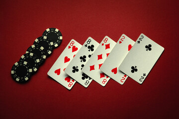 Great luck in the card game of poker with a winning combination of full house or full boat. Playing cards and chips are laid out in a club on a red table