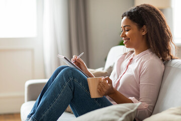 Obraz premium Joyful Moments: Young Woman Journaling with Coffee at Home