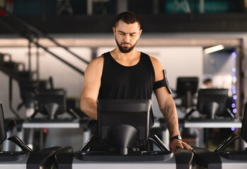 Handsome Millennial Man Exercising on Treadmill in Gym