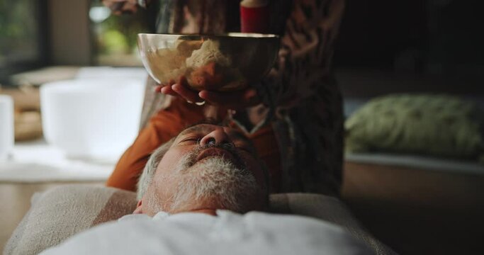 Sound, meditation and relax with Tibetan singing bowl for indigenous spiritual healing in holistic practice. Soul, music and senior man listen to calm vibration of metal instrument to balance chakra